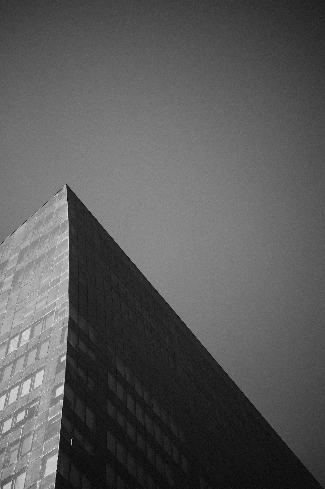 Dramatic black and white photo of a modern building against a clear sky.